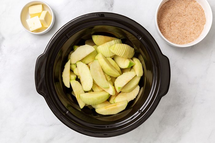 Chopped granny smith apples in a slow cooker for step two of Cinnamon Apples recipe for Taste of Home