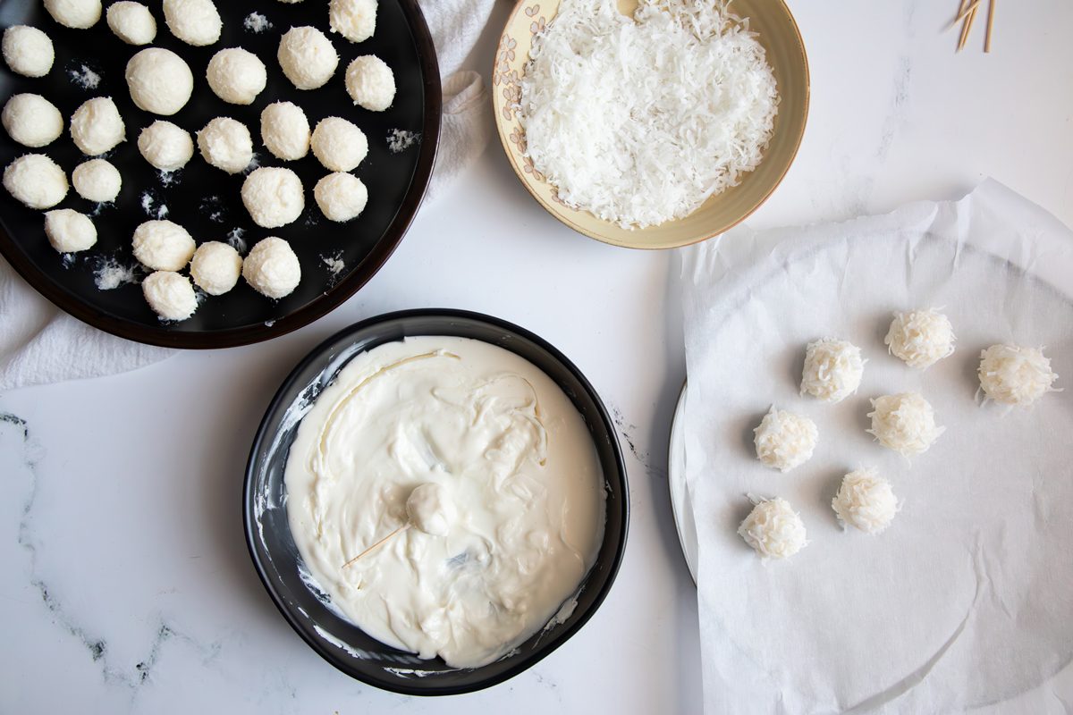 Overhead shot for Taste of Home Coconut Snowballs, dipping into white chocolate mixture.