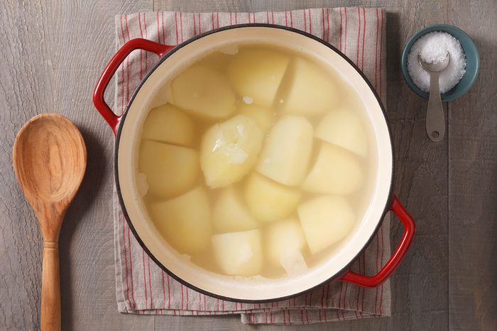 potatoes in water a stockpot with a small container of salt next to it.