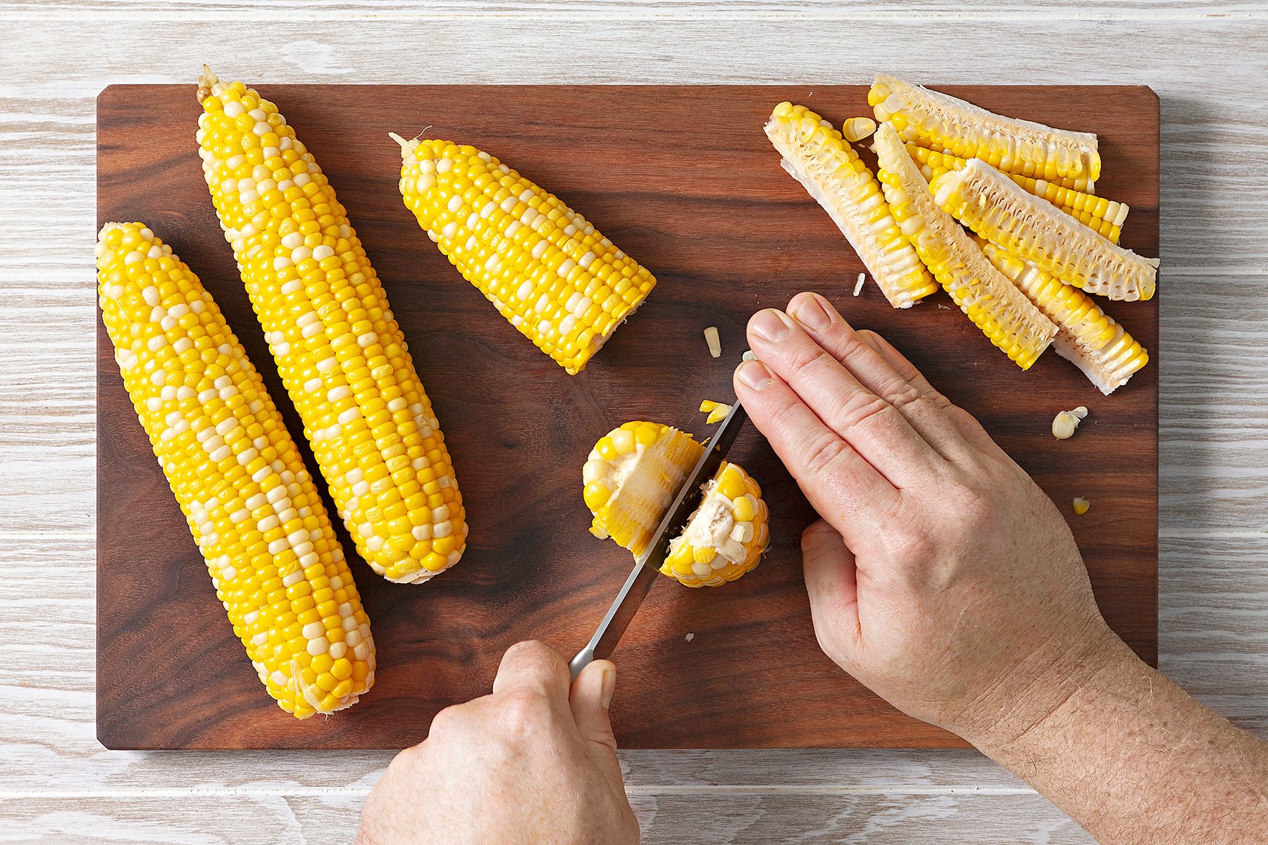 Overhead shot of slice each half into quarters; knife; wooden chopping board; wooden surface;