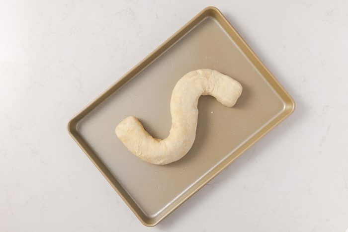 Dough being shaped into an S on baking tray.