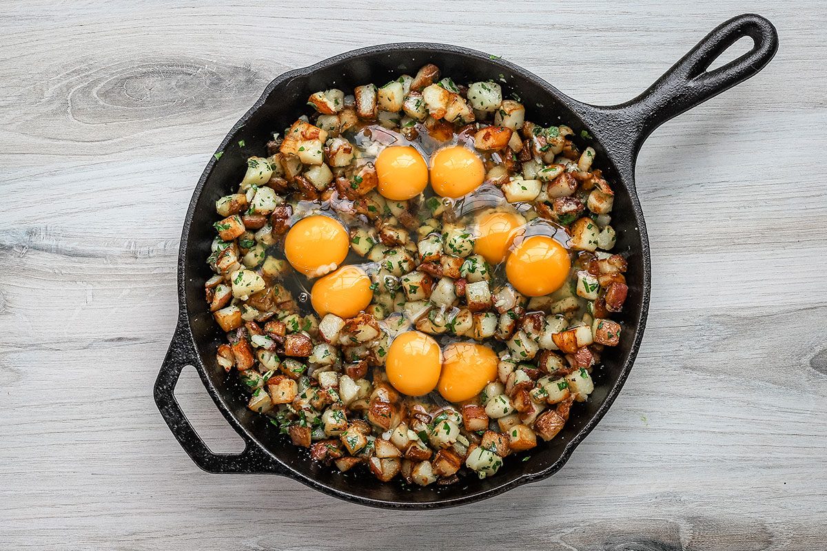 Eggs are added to the potatoes in the cast iron skillet and the dish is ready for the oven.