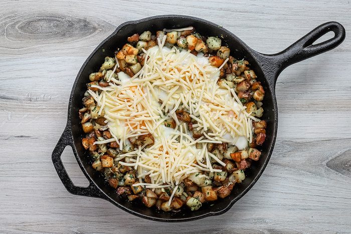 Cheddar cheese is added to the potatoes and eggs and the skillet is returned to the oven.
