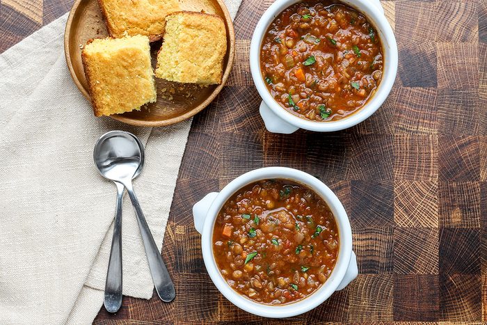 Overhead shot of Instant Pot lentil soup garnished with parsley and cornbread on the side.