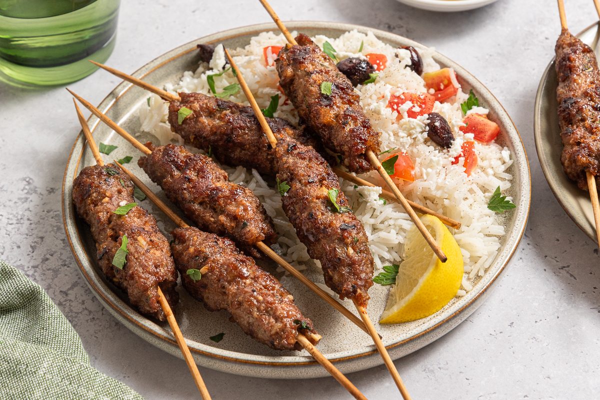 Kofta Kabob Served With Rise, Olives, Tomatoes, Feta And Lemon