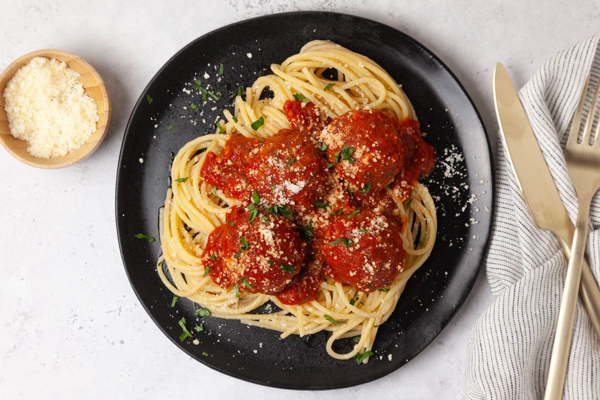 Single serving of Taste of Home Lentil Meatballs in marinara sauce, on spaghetti, garnished with parmesan and parsley