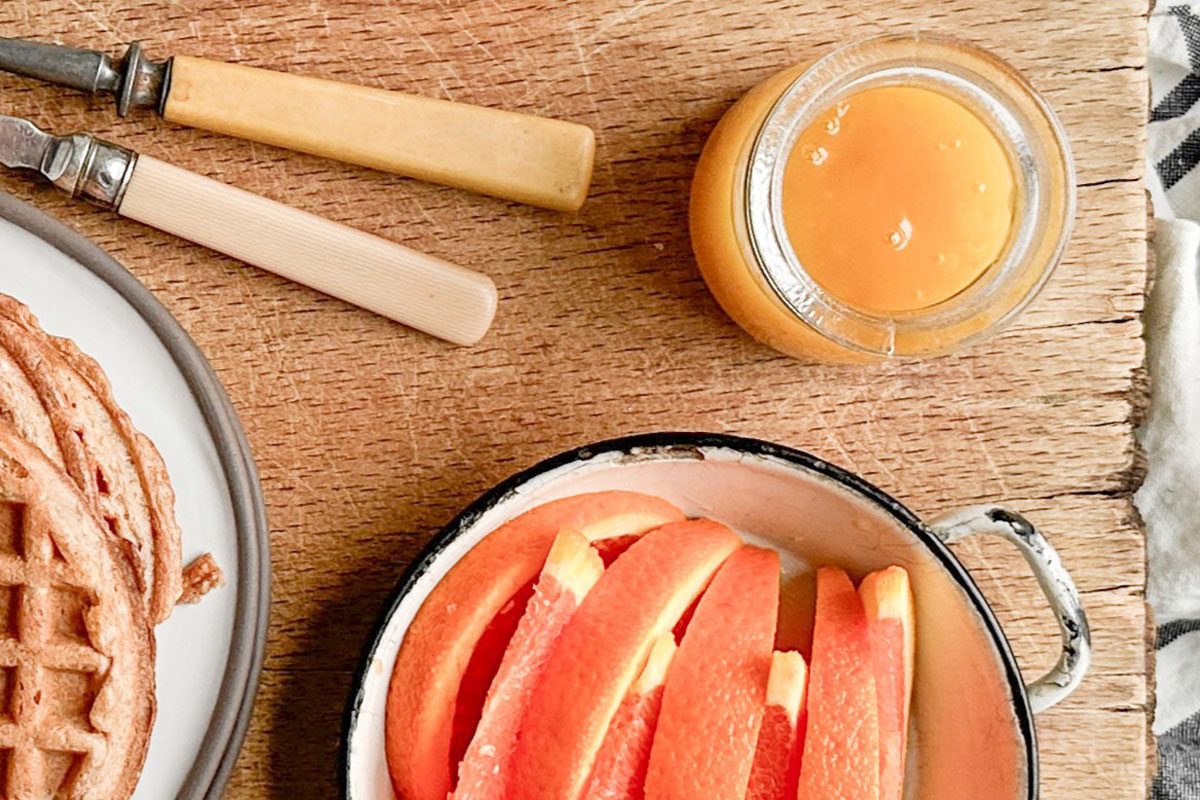 Taste of Home Orange Syrup with waffles and orange slices on a wooden board