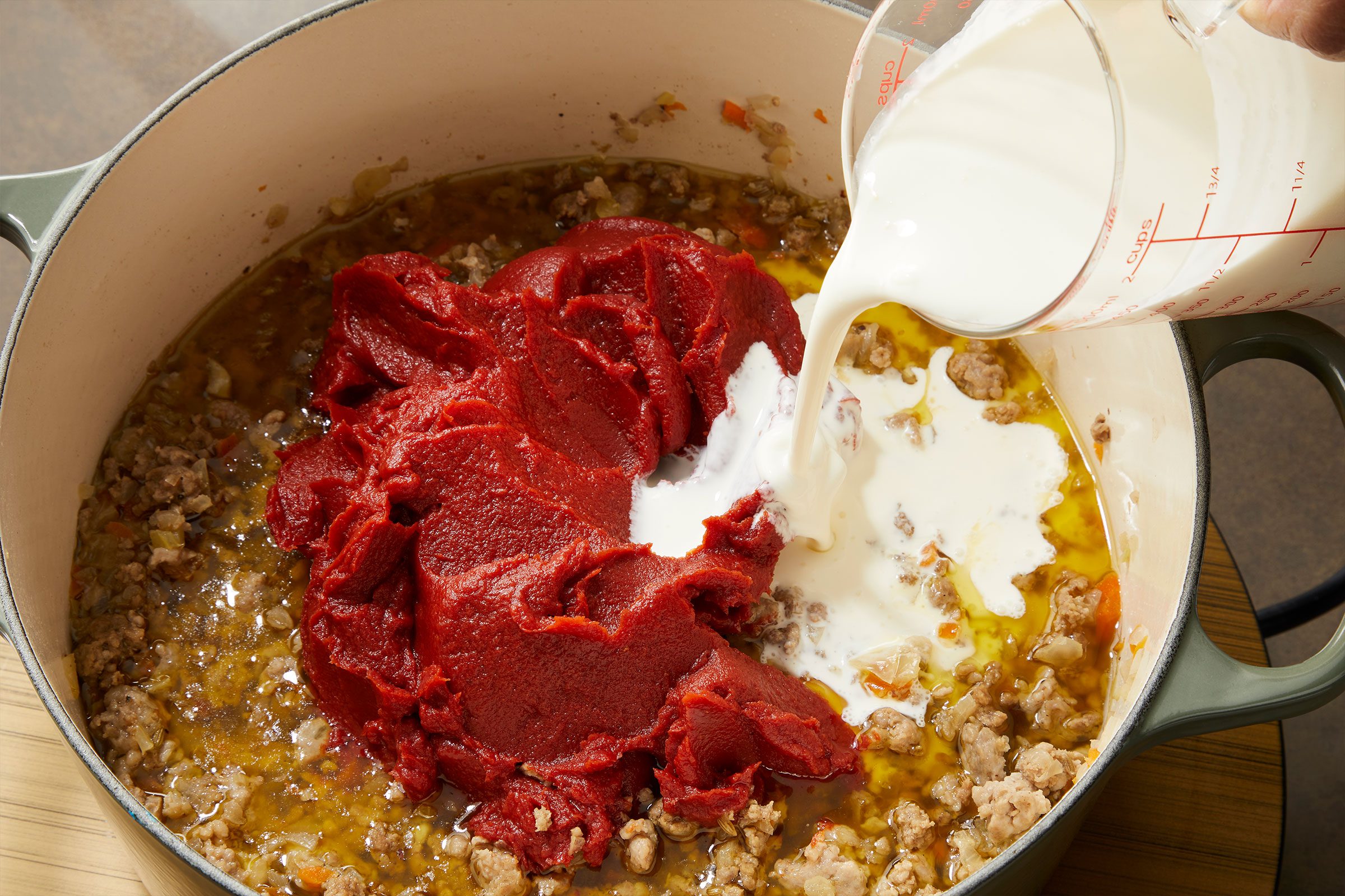 cream and tomato paste in a Dutch oven to prepare pappardelle bolognese