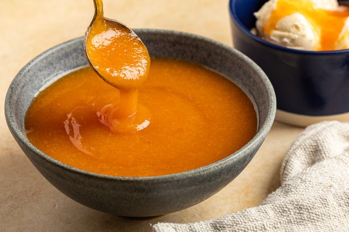 Taste of Home Peach Syrup photo of the finished recipe poured over ice cream.