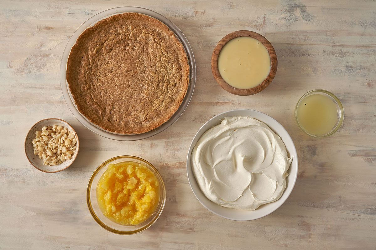 detailed look at the ingredients for Pineapple Pie, featuring condensed milk, crushed pineapple, whipped topping, graham cracker crust, and toasted macadamia nuts, from Taste of Home.