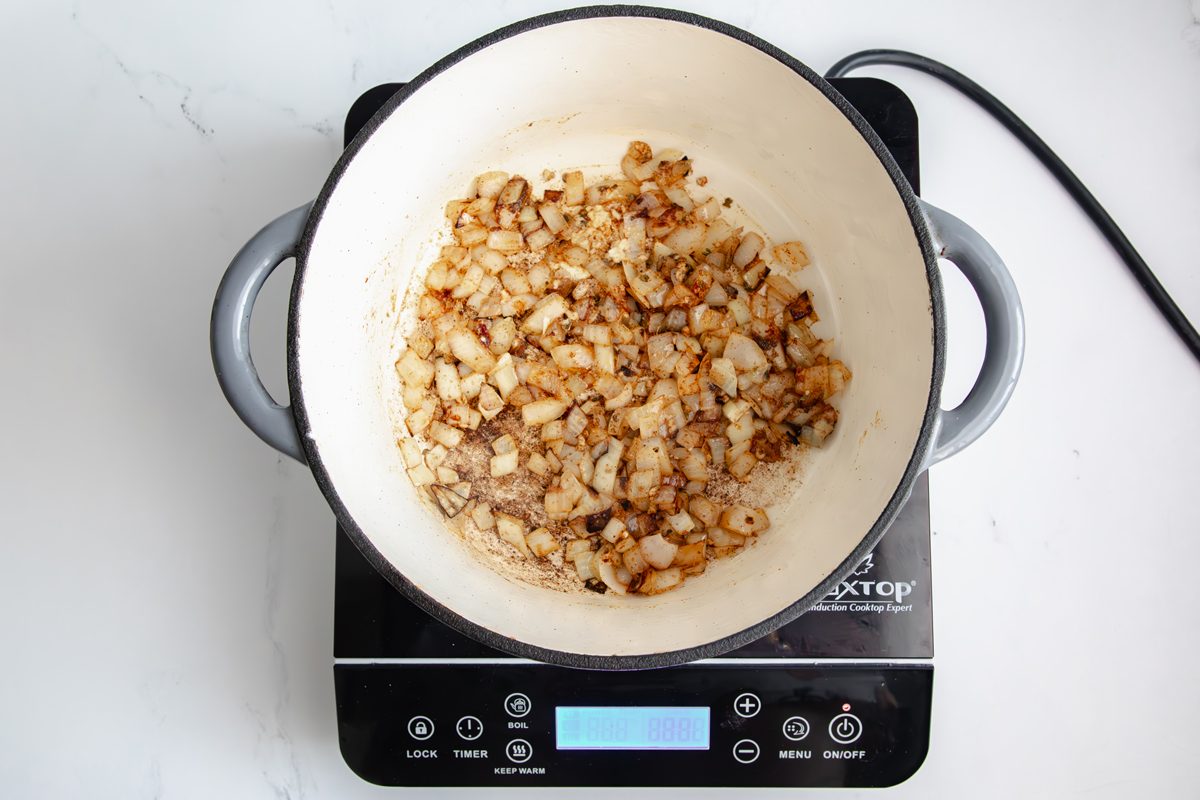 Overhead shot for Taste of Home Pinto Bean Soup, aromatics and spices cooking in a large dutch oven.