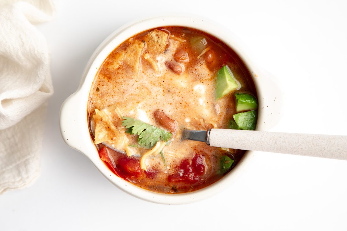 Beauty shot for Taste of Home Pinto Bean Soup being served in a bowl with toppings mixed together.