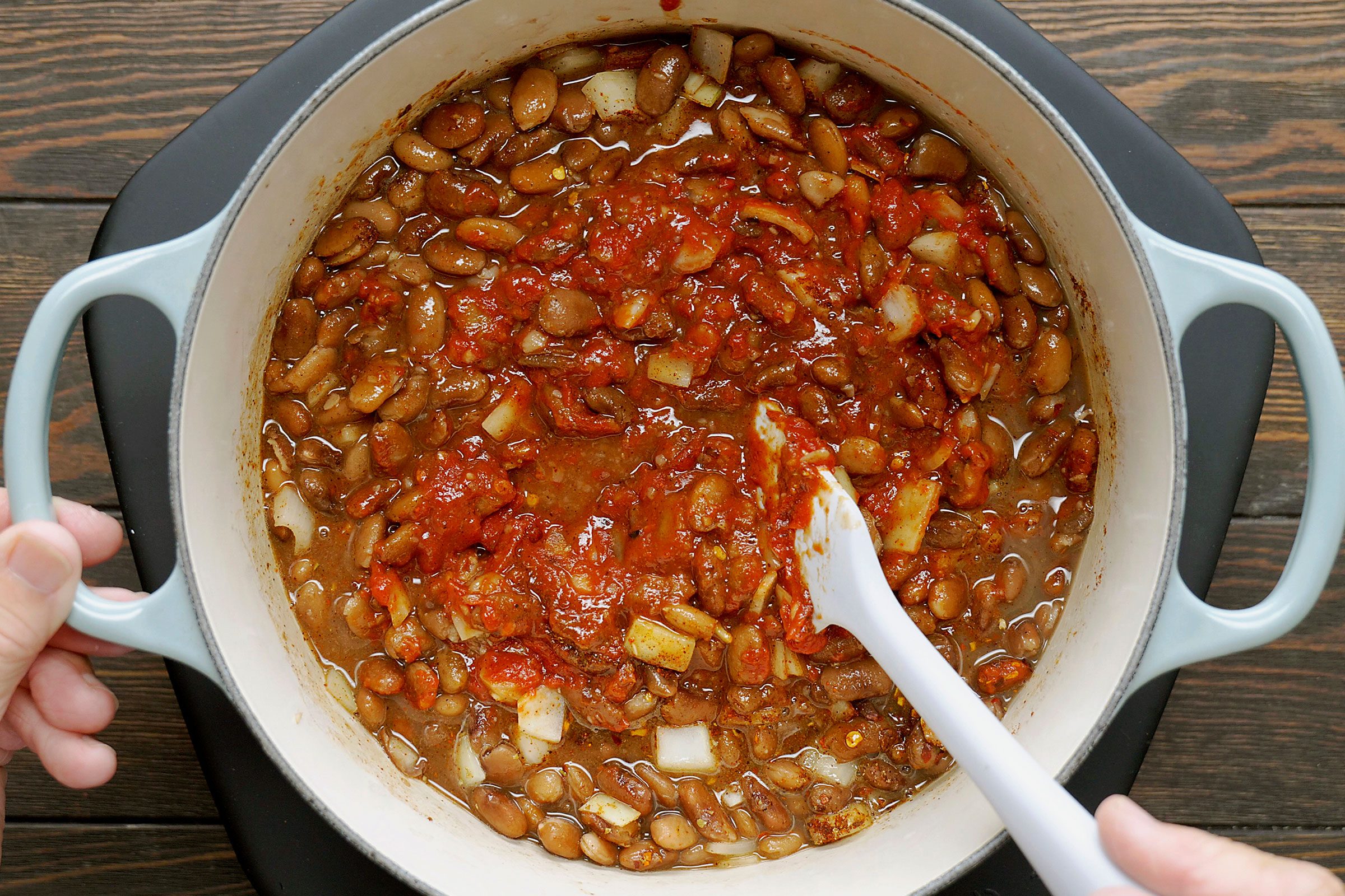 Adding other ingredients to boiled beans in a dutch oven