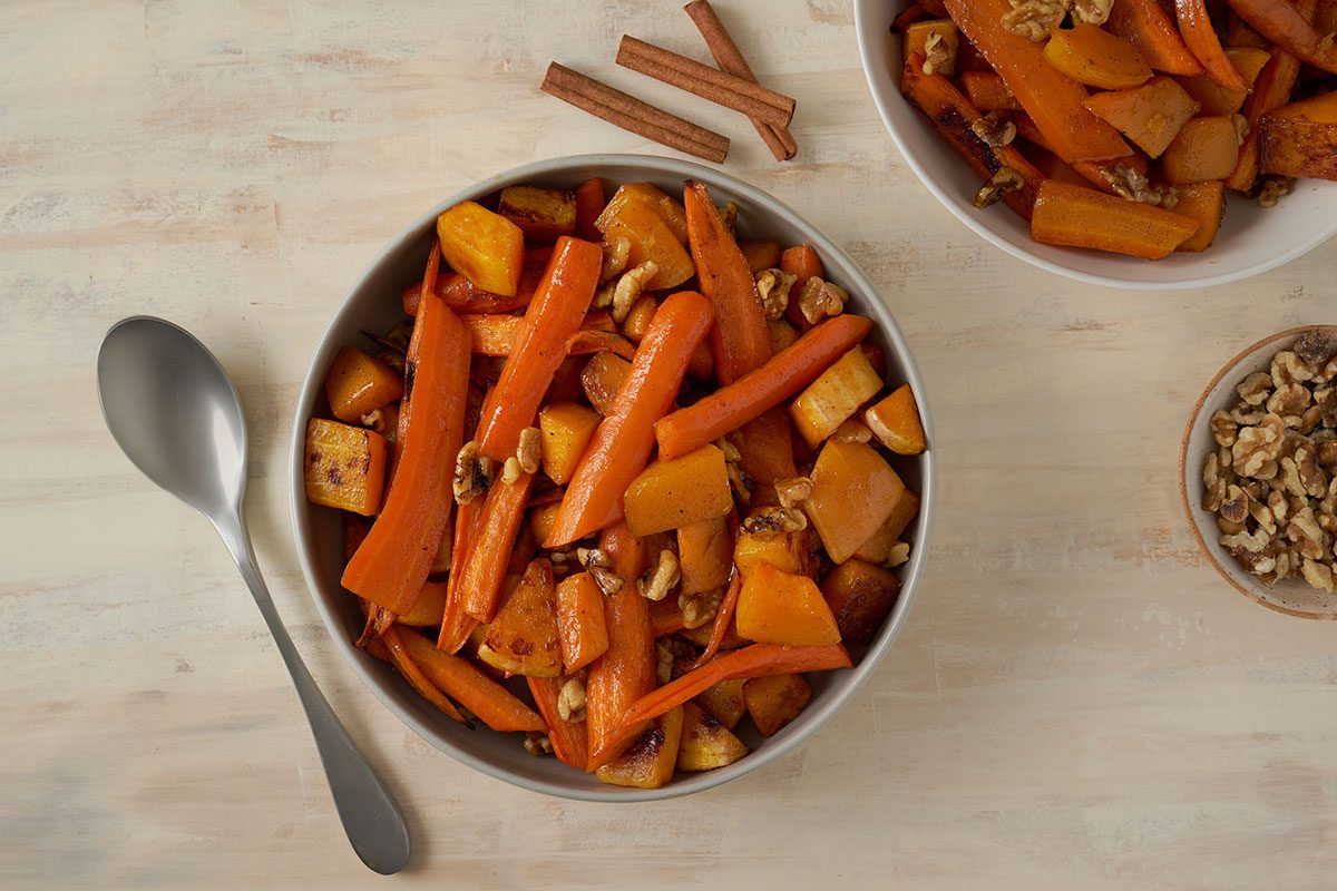 Overhead hero shot of the finished Taste of Home Roasted Vegetables with Walnuts, showing the golden brown roasted squash and carrots topped with toasted walnuts, served on a platter.