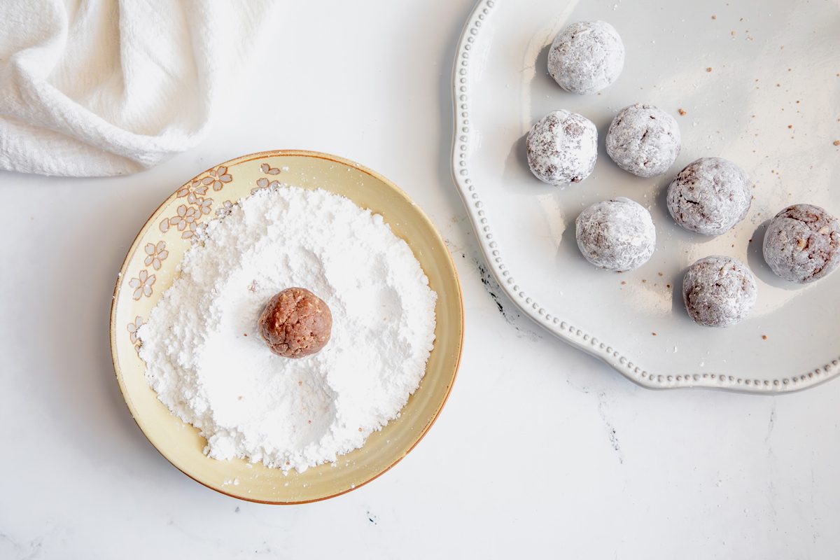 Overhead shot for Taste of Home Rum Balls, with rum balls being tossed in powdered sugar.