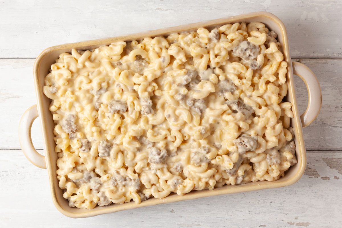 Step 4 of Taste of Home Sausage Mac and Cheese is to Transfer the mixture to a greased 13x9-inch baking dish. Bake until the cheese is bubbly and the edges are golden brown, about 20 to 25 minutes.