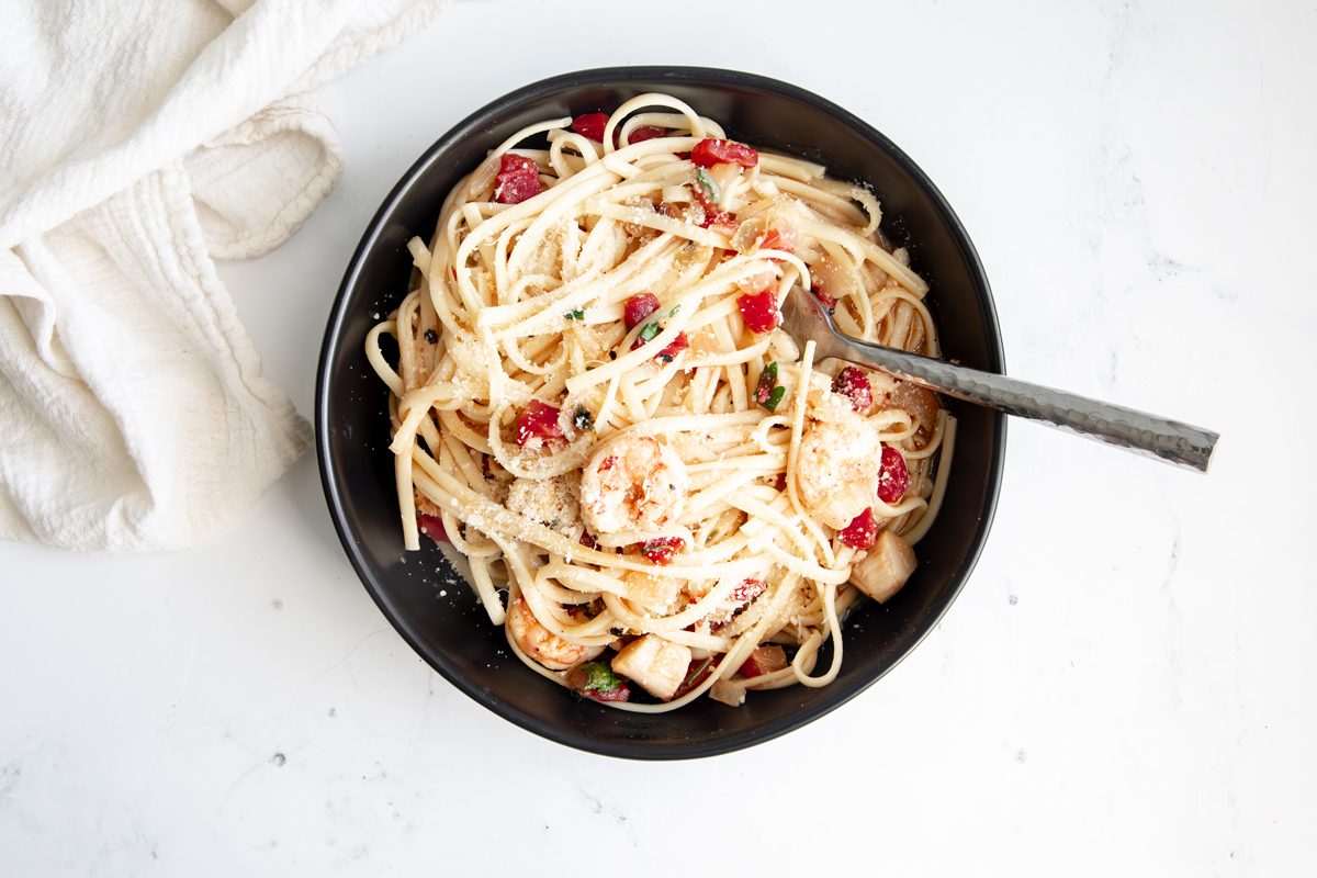 Close up beauty shot for Taste of Home Seafood Linguine being served in a black bowl topped with parmesan cheese.