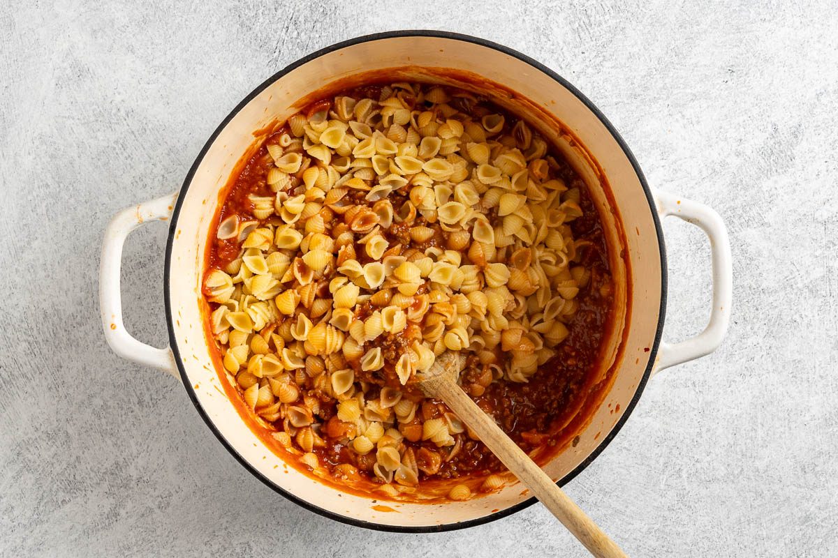 Taste of Home Sloppy Joe Pasta photo of the tomato sauce, tomatoe paste, sloppy joe seasoning and the pasta added to the Duch oven.