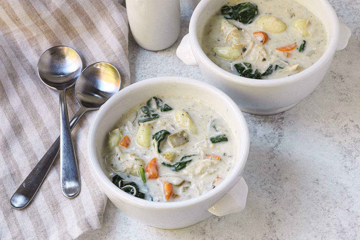 Servings of slow cooker chicken gnocchi soup with spinach and vegetables.