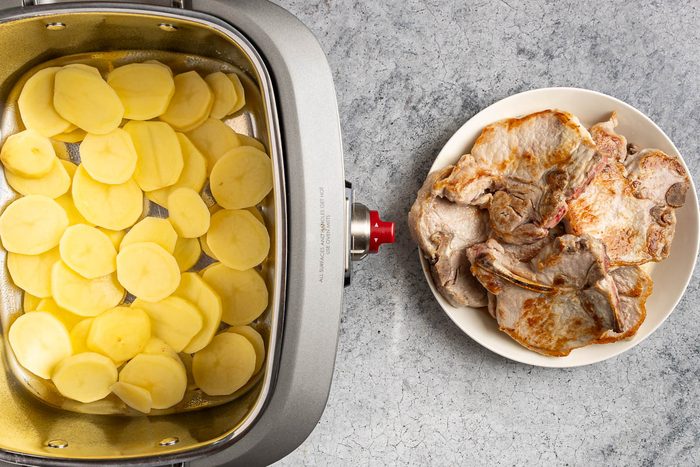 Taste of Home Slow Cooker Pork Chops and Potatoes photo of the potatoes in the slow cooker and the browned pork chops.
