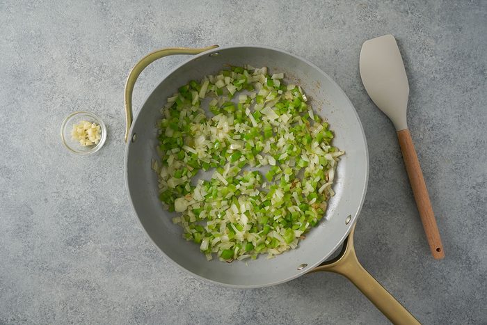 Overhead view of freshly chopped green peppers, onions, and garlic sauteing in olive oil in a nonstick skillet for the Taste of Home Southwest Rice recipe.