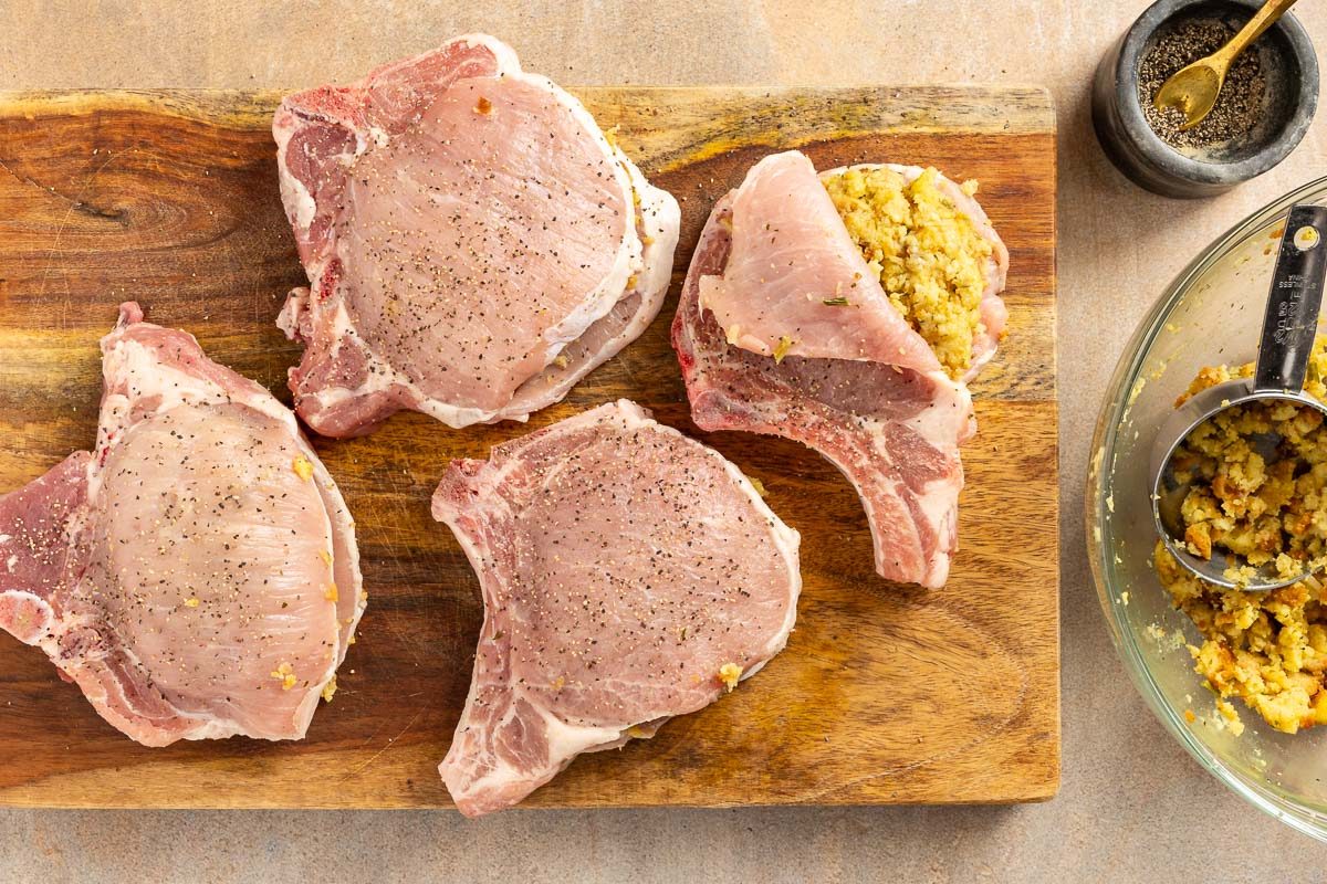 raw pork chops with stuffing on a cutting board