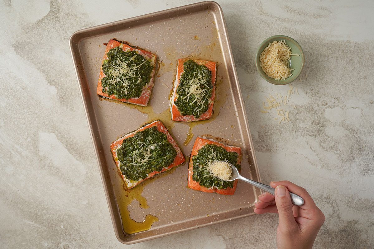 Overhead view of baked salmon fillets being topped with Parmesan cheese for the Taste of Home Basil Salmon recipe.