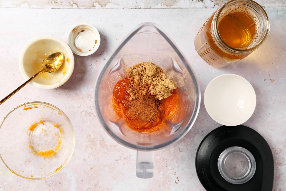 Process of making Taste of Home's Pumpkin Juice in a large pitcher on a grey marble surface.