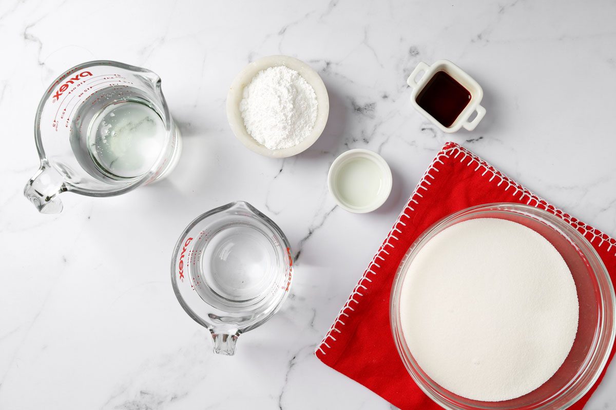 Ingredients for Taste of Home's cinnamon hard candy laid out in small bowls on a white marble surface.