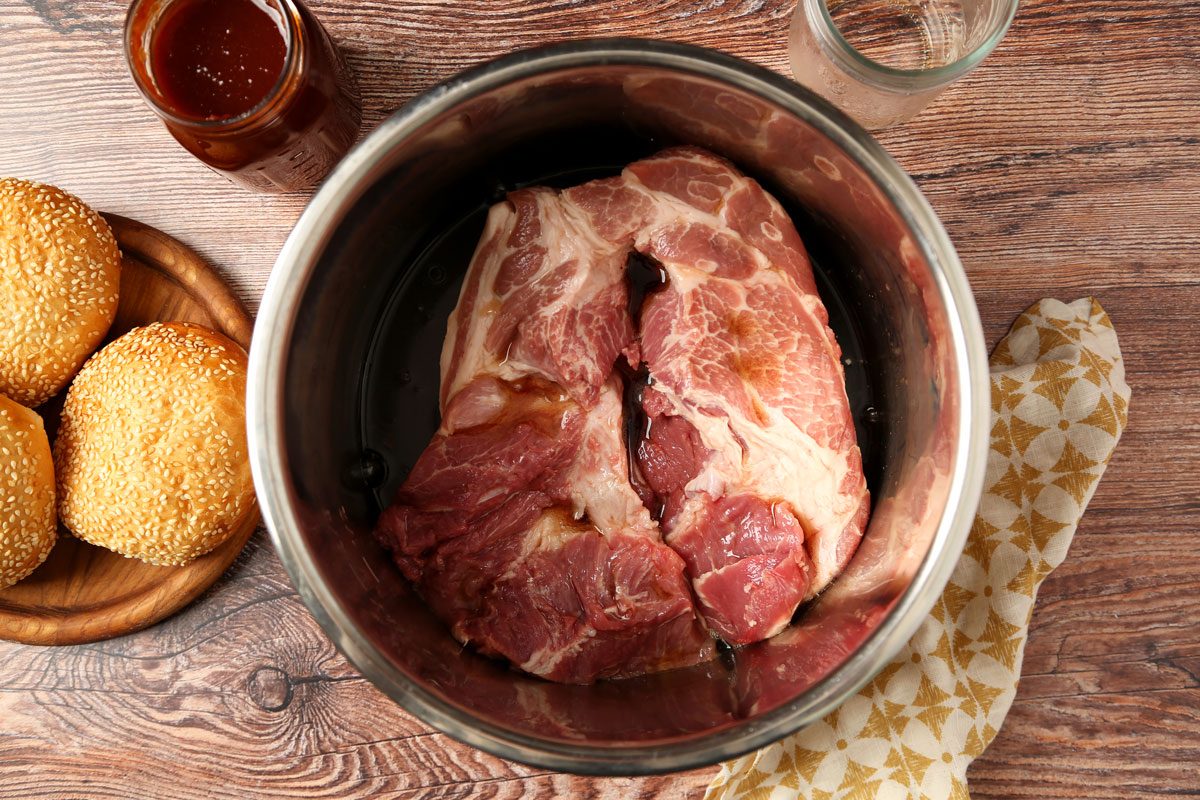 Process of making. Taste of Home's Root Beer Pulled Pork laid out in small bowls on a brown wooden surface.