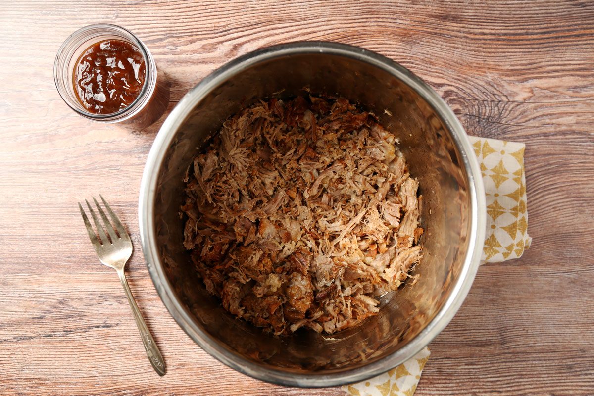 Process of making. Taste of Home's Root Beer Pulled Pork laid out in small bowls on a brown wooden surface.