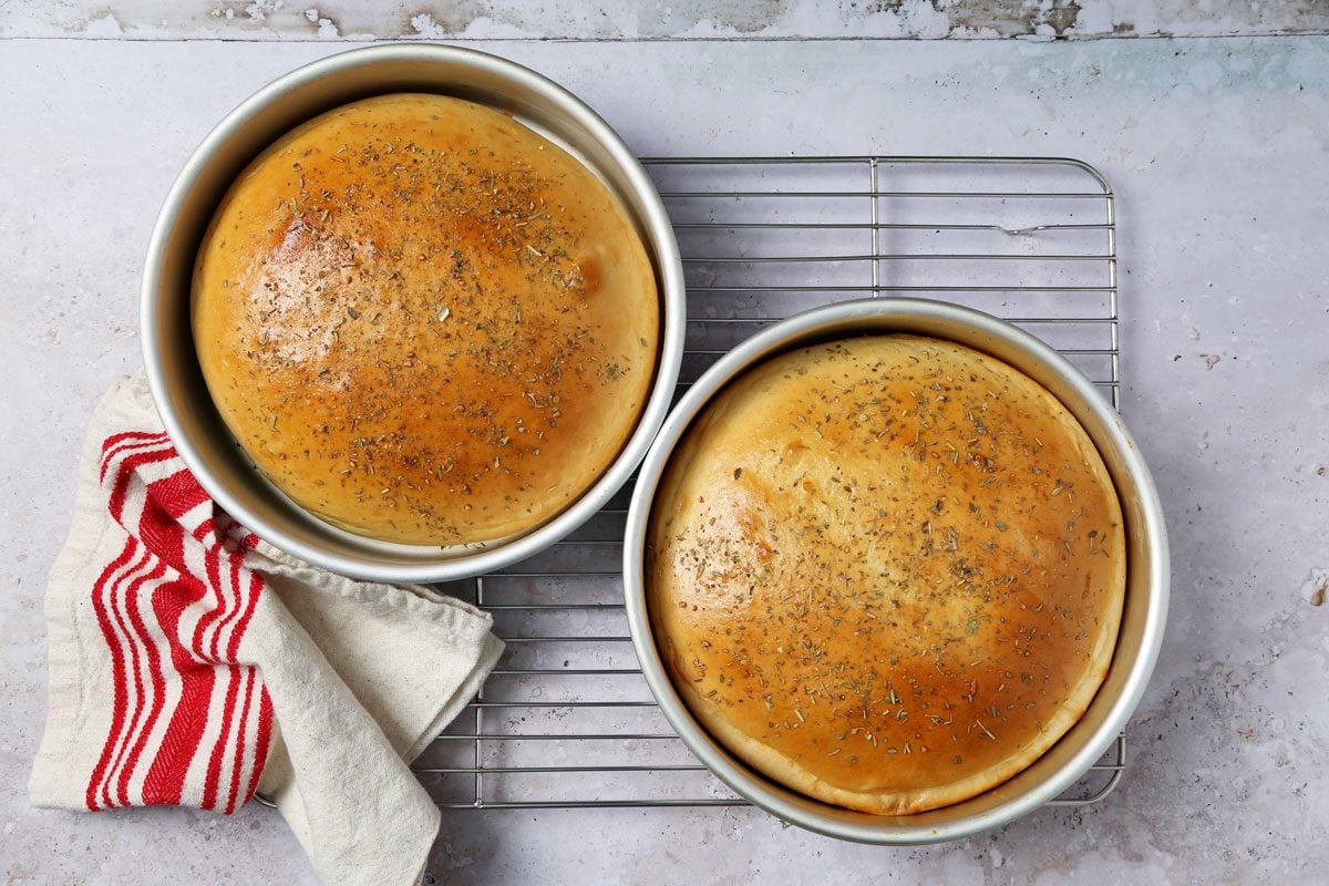 Process of making Taste of Home's Italian Sweet Bread loaves cooling on a wire rack on a grey and beige surface.