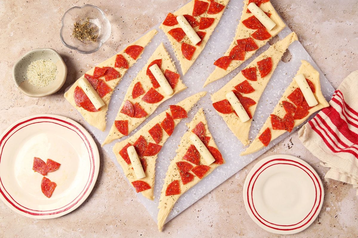 Process of making Taste of Home's Pepperoni Rolls crescent roll filled with pepperoni and cheese on a brown and beige marble surface.