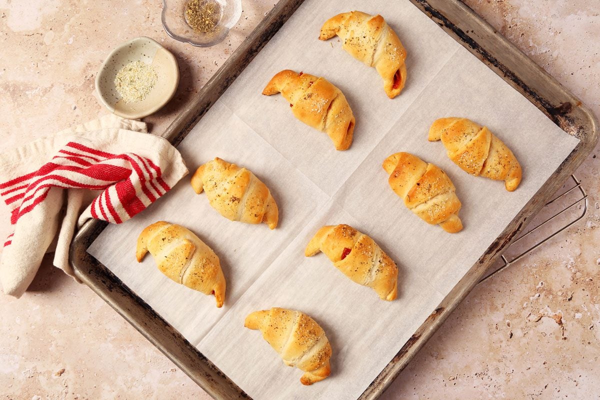 Process of making Taste of Home's Pepperoni Rolls baked on a baking sheet on a brown and beige marble surface.