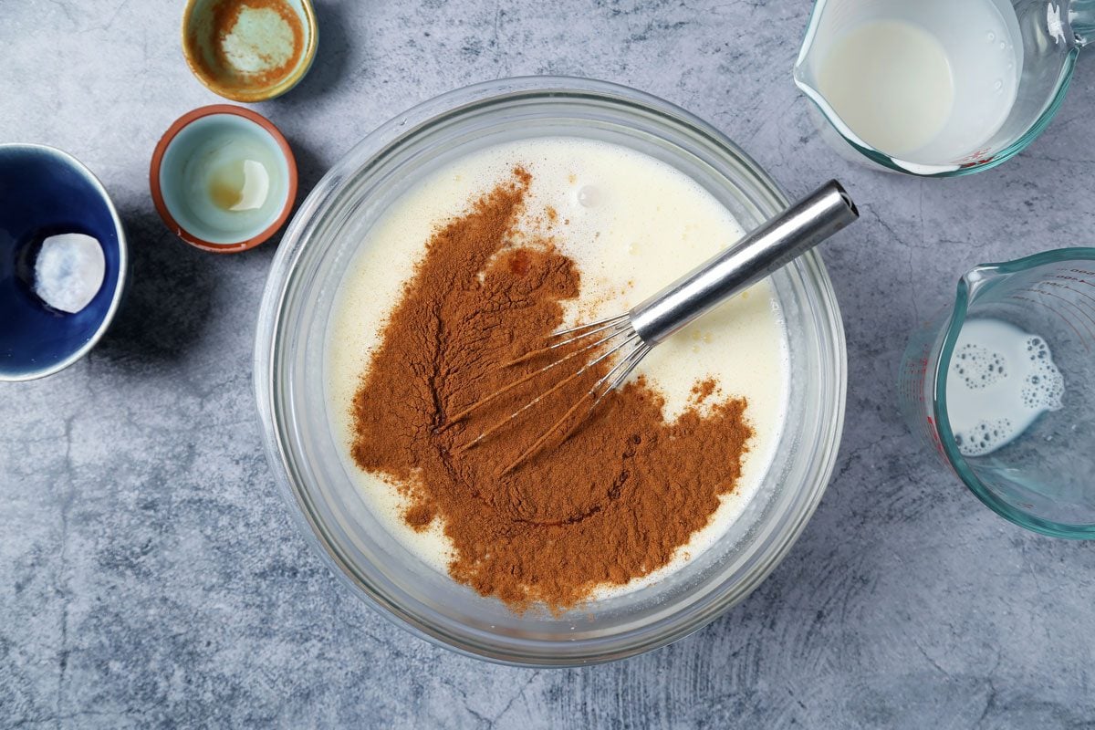 Ingredients for Taste of Home's Cinnamon Ice Cream laid out in small bowls on a blue marble surface.