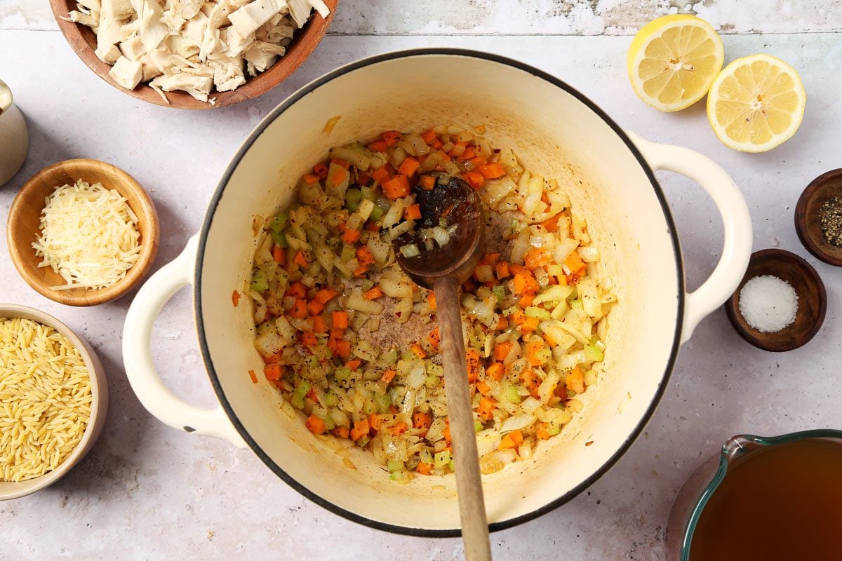 process of making Taste of Home's Chicken Florentine Soup in a dutch oven on a grey surface.