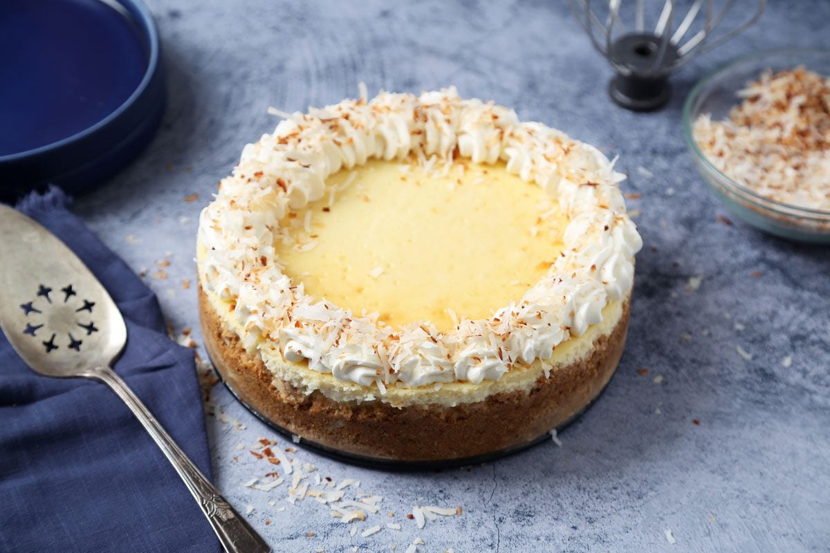 Close up of Taste of Home's Coconut Cheesecake served on blue plates on a dark blue surface.
