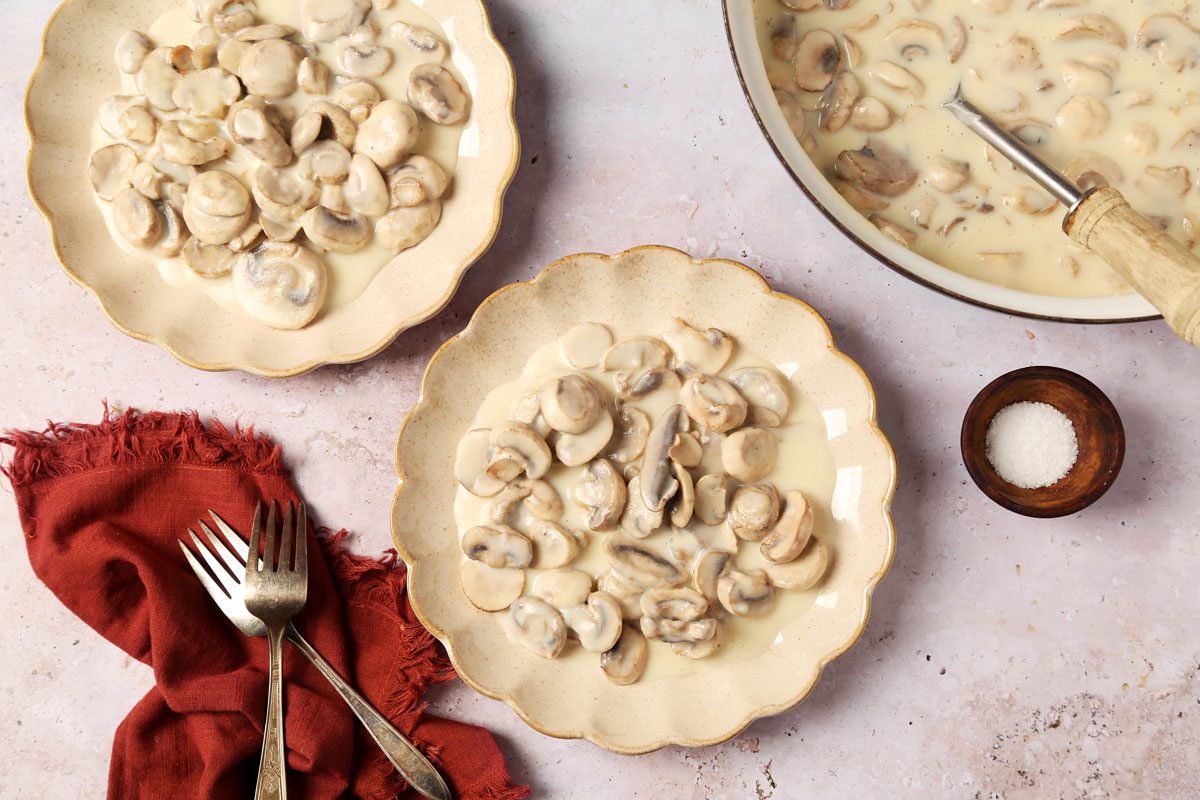 Close up of Taste of Home's Creamed Mushrooms served on brown plates on a grey surface.
