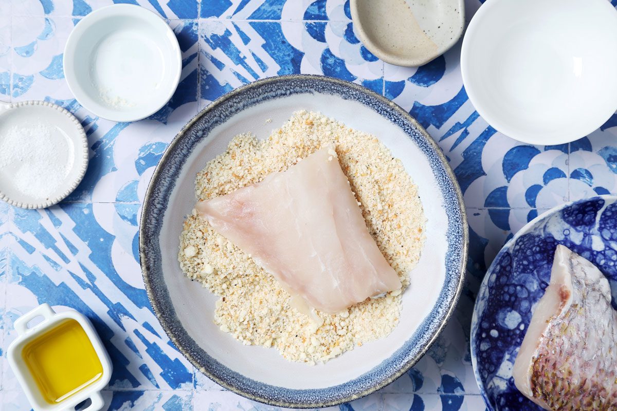 Process of making Taste of Home's Pan-Seared Red Snapper laid seared in a pan on a blue and white tiled background.