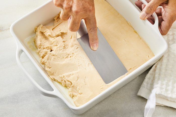 3/4th shot of using a spatula to flatten dough in one layer in baking dish;