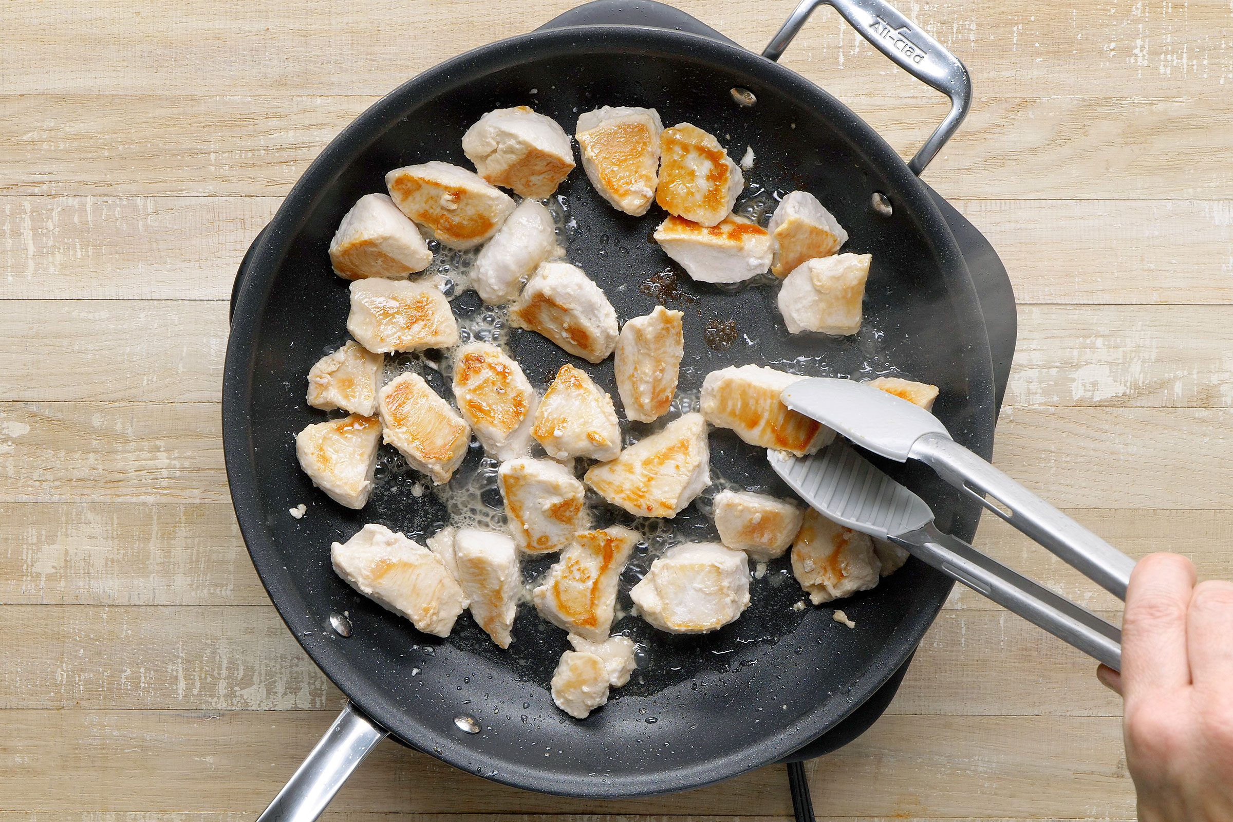 Cooking chicken in canola oil in a large skillet