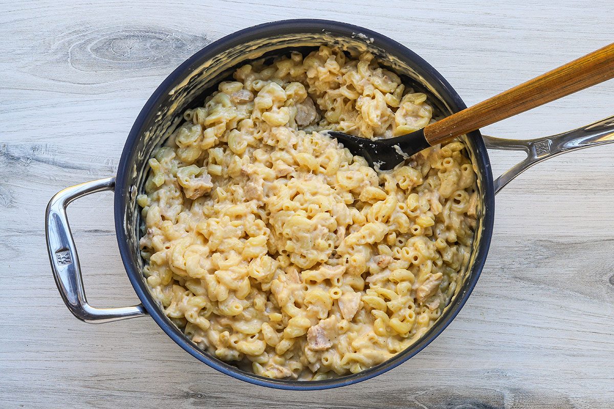 Tuna mac and cheese preparation: combining the macaroni with the cheese sauce.