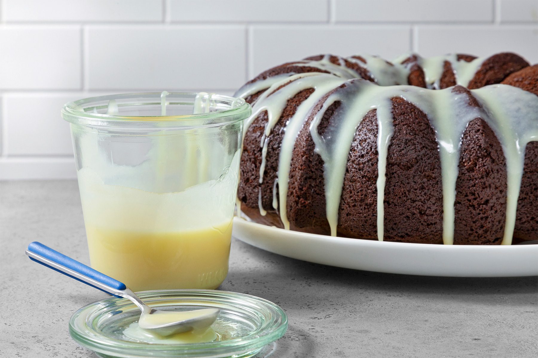 Table view shot of White Chocolate Sauce; transfer into jar with lid; spoon over cake; grey surface;