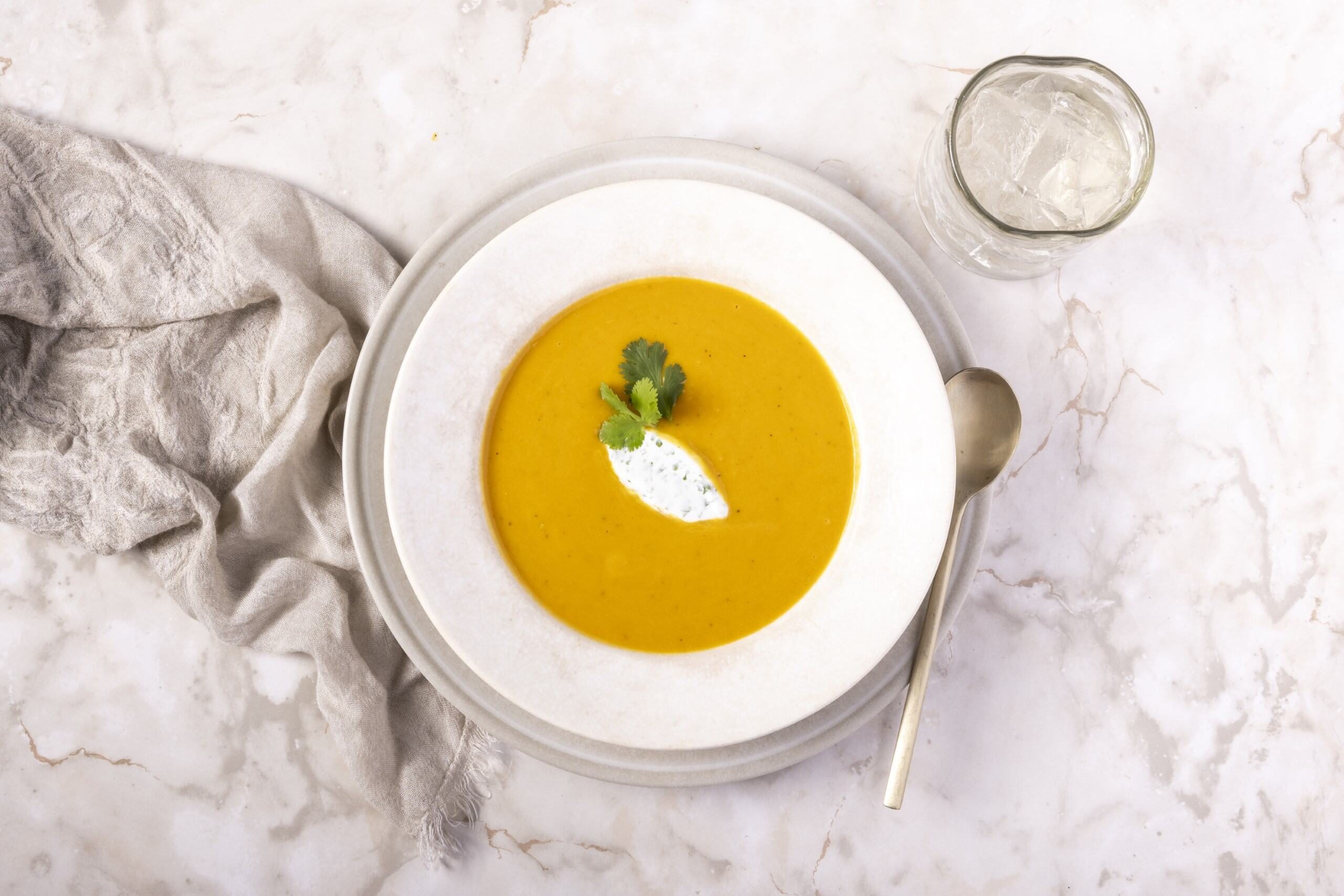 Curried Butternut Squash Soup in a white bowl 3/4 view on marble table