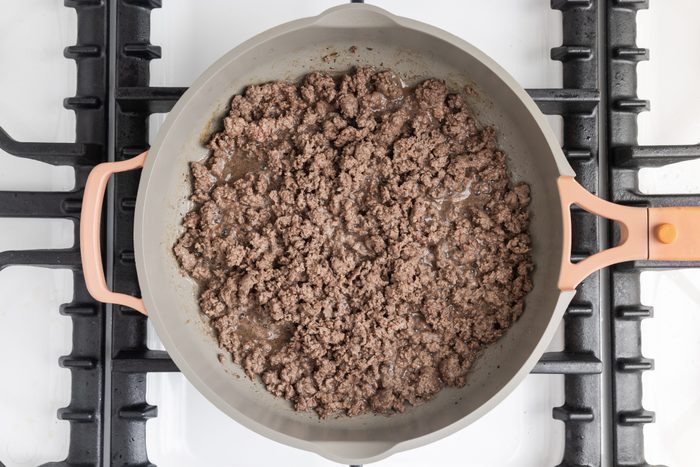 Ground beef cooking in skillet.