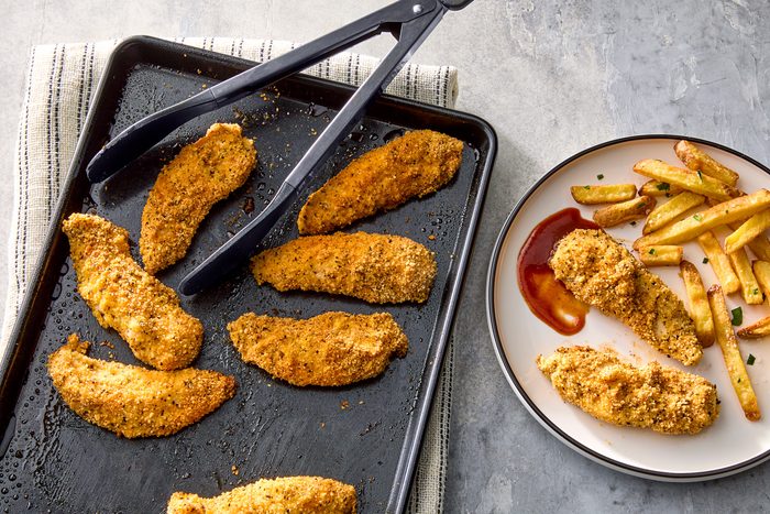 Seasoned chicken strips on a baking sheet.