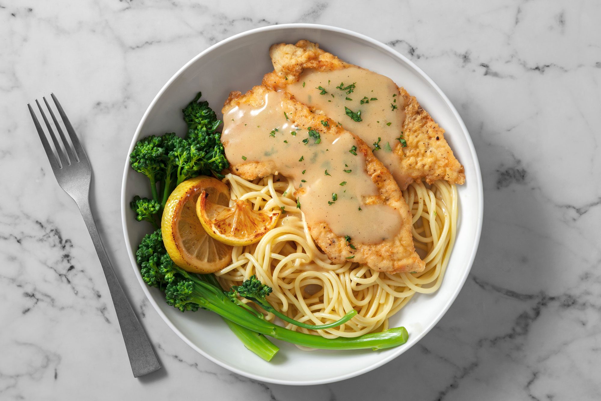 Chicken francese served with noodles and lemon wedges