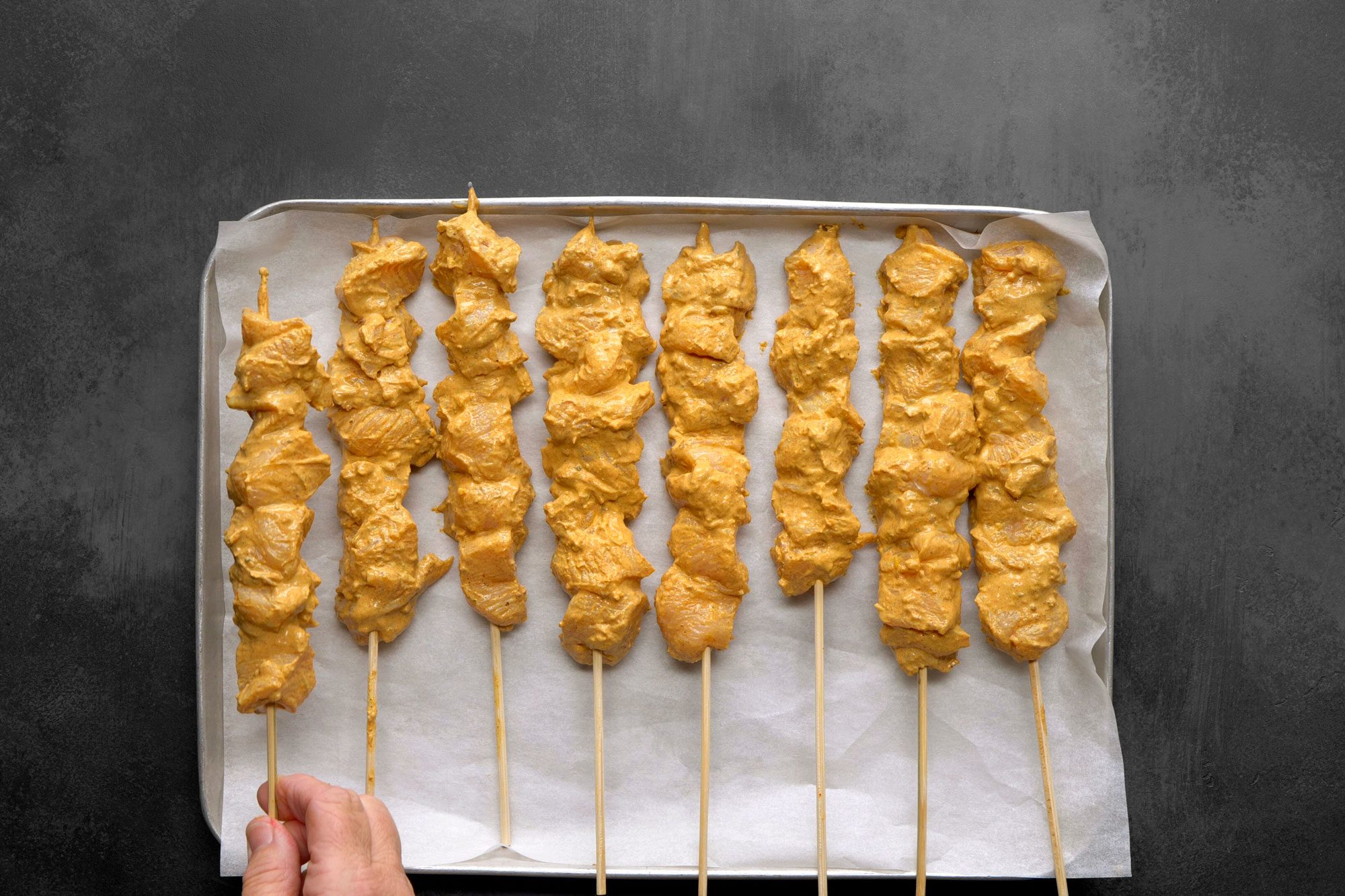 Chicken skewers are resting on a sheet of parchment paper