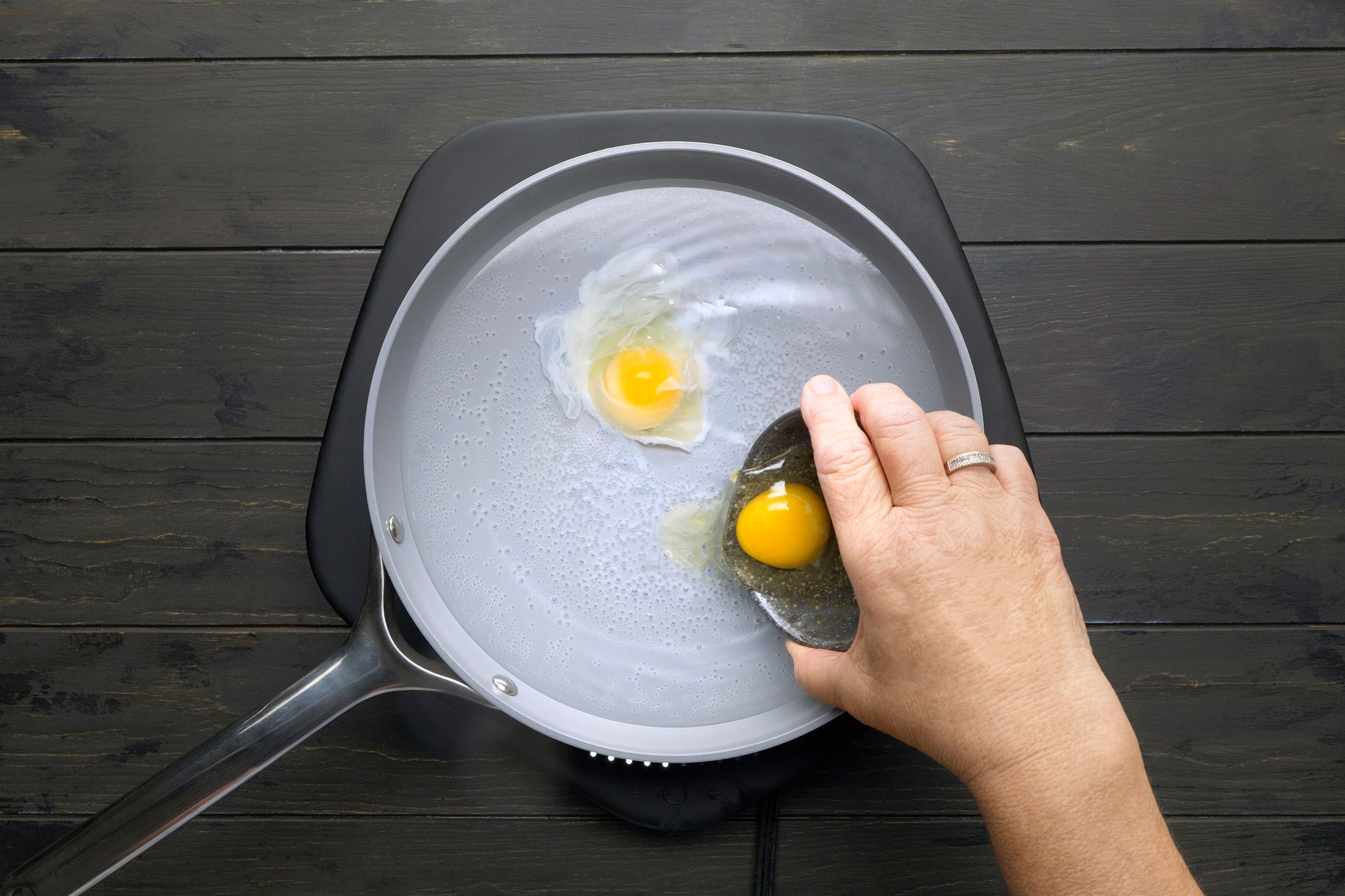 Breaking eggs in a large saucepan with water in it