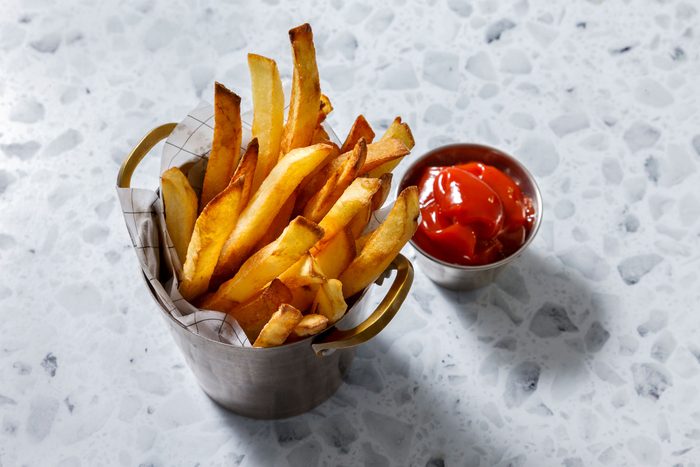 Pan fried french fries in a metal utensil with ketchup on side